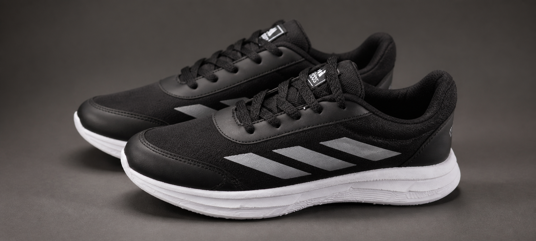 Par de zapatillas negras con detalles grises y suela blanca